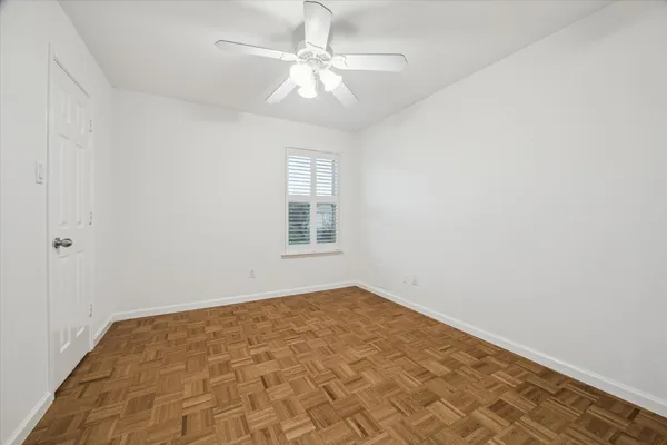 an empty room with a chandelier fan and windows