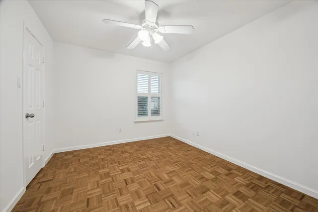 an empty room with a chandelier fan and windows