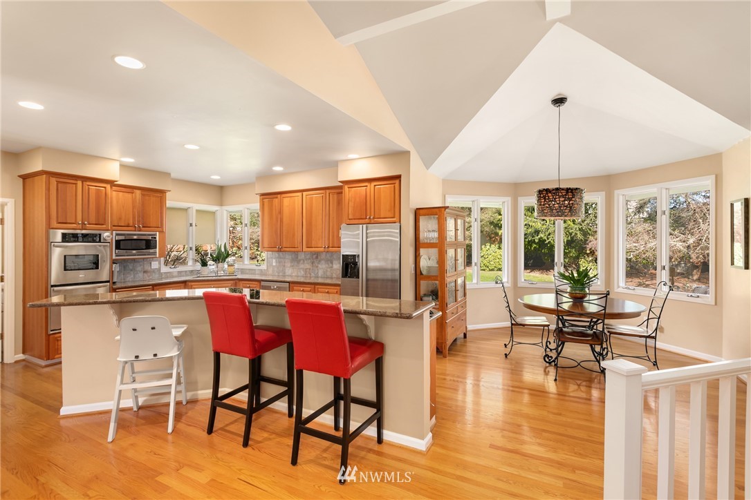 21731 35th Avenue Southeast Bothell, WA 98021 - Photo 9 of 36 a kitchen with stainless steel appliances granite countertop a stove top oven a refrigerator a dining table and chairs with wooden floor