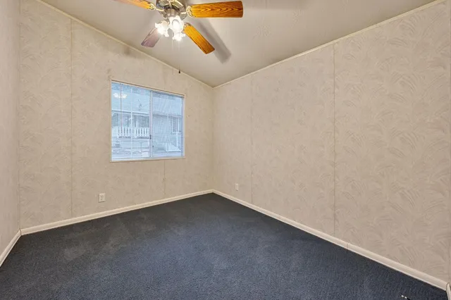 an empty room with a window and a ceiling fan
