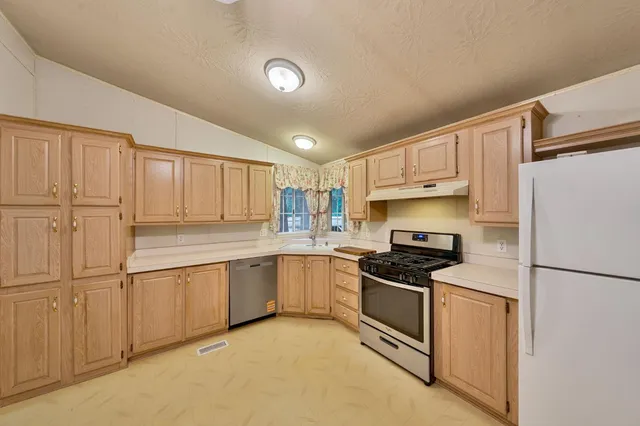 a kitchen with granite countertop a refrigerator sink stove and cabinets