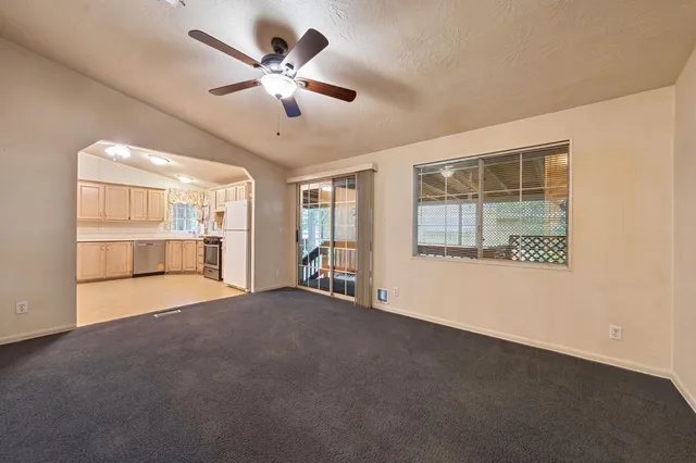 a view of an empty room with a window and a kitchen