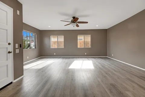 a view of empty room with wooden floor and fan