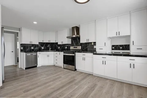 a kitchen with granite countertop white cabinets and white appliances