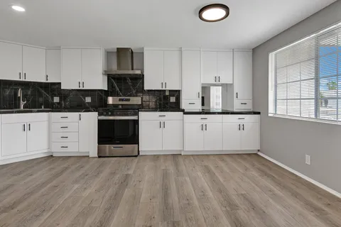 a kitchen with stainless steel appliances granite countertop a stove top oven a sink and white cabinets