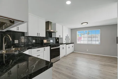 a large kitchen with stainless steel appliances granite countertop a stove a sink and a refrigerator