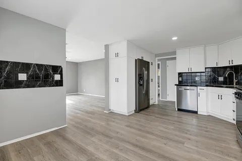 a kitchen with stainless steel appliances granite countertop a refrigerator sink and white cabinets