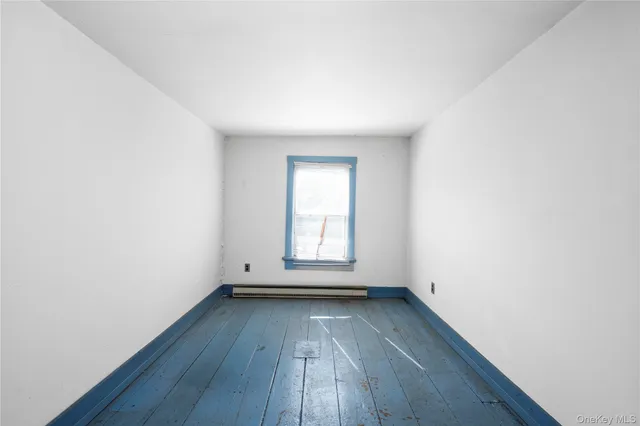 an empty room with wooden floor and window