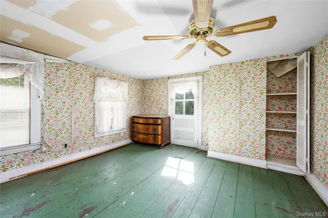 a view of an empty room with a window and kitchen view