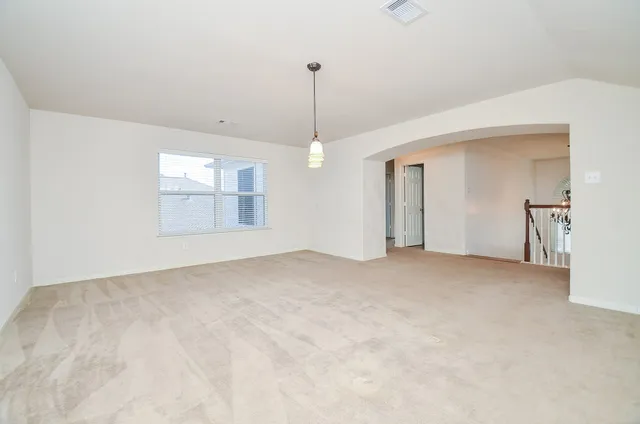 a view of an empty room with chandelier and window