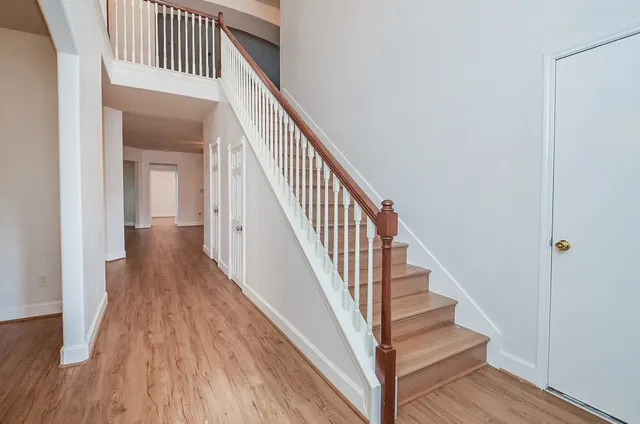 a view of a hallway with wooden floor and staircase