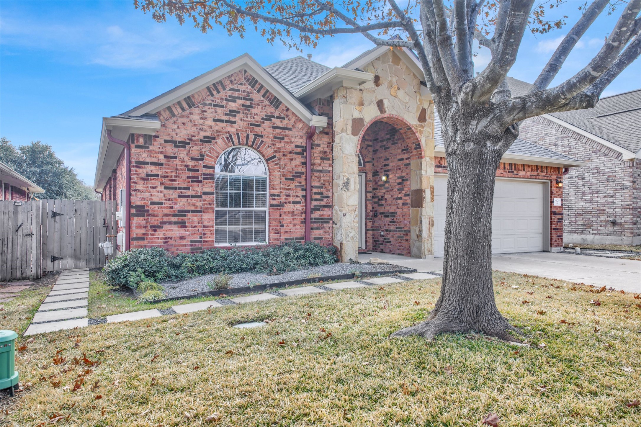 View of front of house with brick siding, a gate, a garage, and concrete driveway