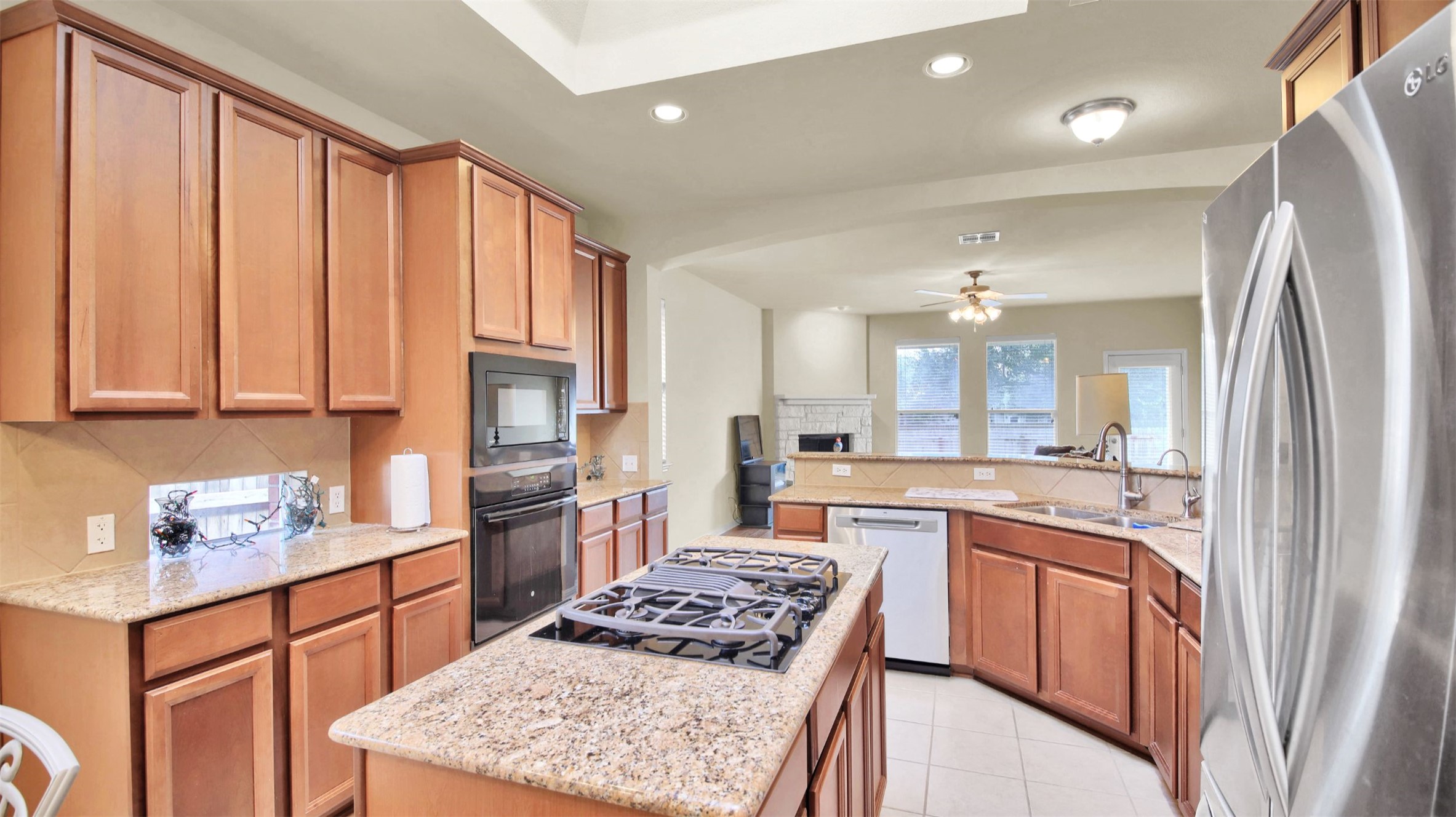 2979 Freemont Street Round Rock, TX 78681 - Photo 14 of 40 Kitchen featuring black appliances, recessed lighting, light stone countertops, a center island, and light tile patterned floors