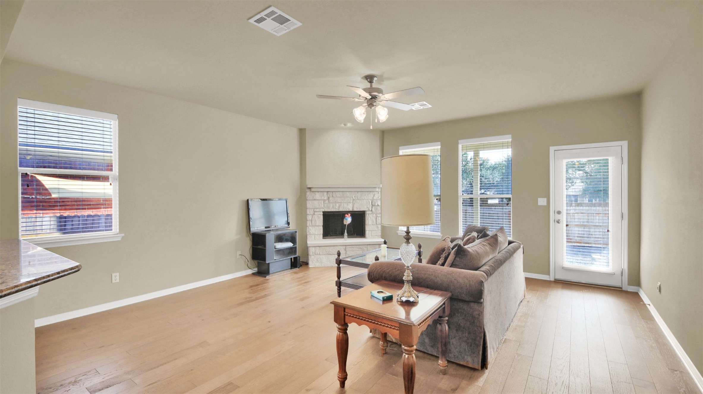 2979 Freemont Street Round Rock, TX 78681 - Photo 20 of 40 Living room featuring light wood finished floors, a stone fireplace, and a ceiling fan