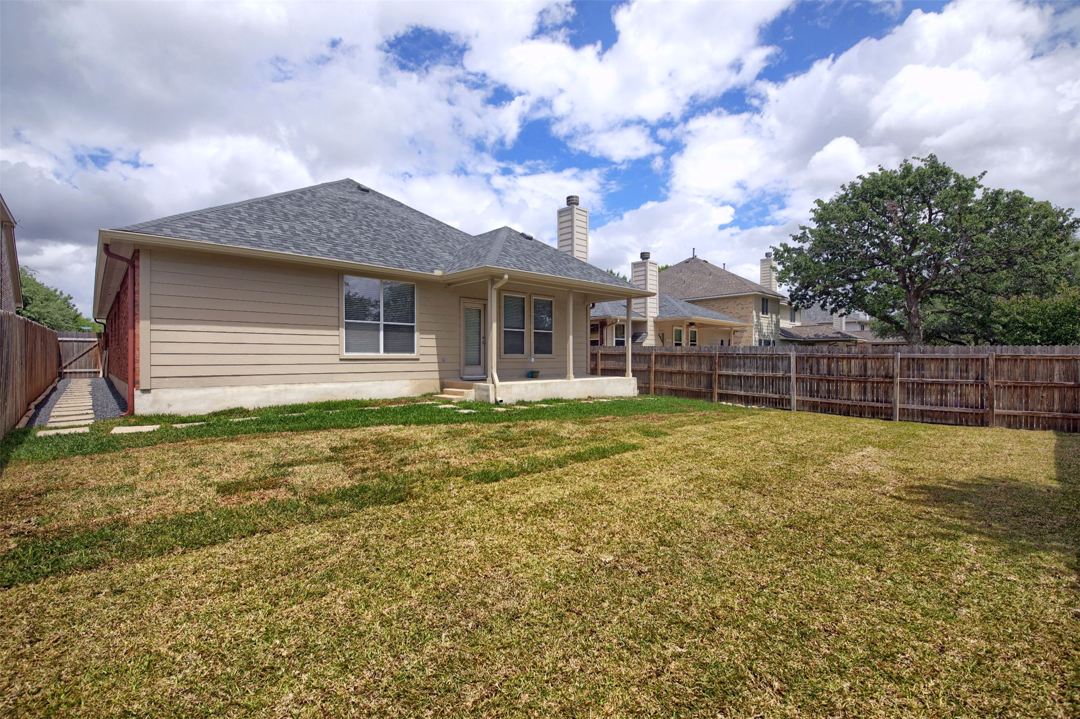 2979 Freemont Street Round Rock, TX 78681 - Photo 37 of 40 The property features a spacious backyard and covered patio with a wooden privacy fence and a paved walkway leading to a side gate