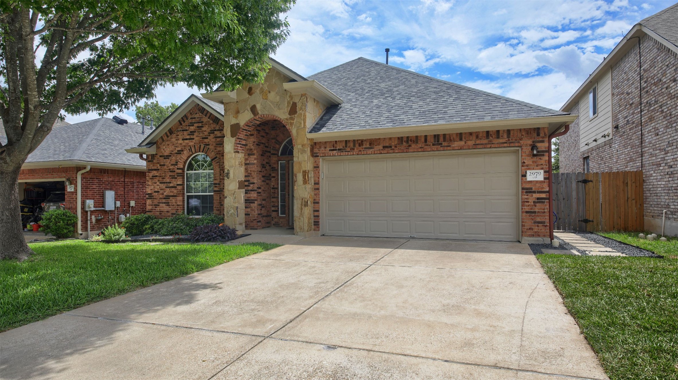 2979 Freemont Street Round Rock, TX 78681 - Photo 4 of 40 The property features a brick exterior with stone accents, a two-car garage, and a concrete driveway