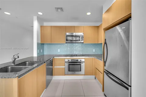 a kitchen with stainless steel appliances granite countertop a sink and a refrigerator