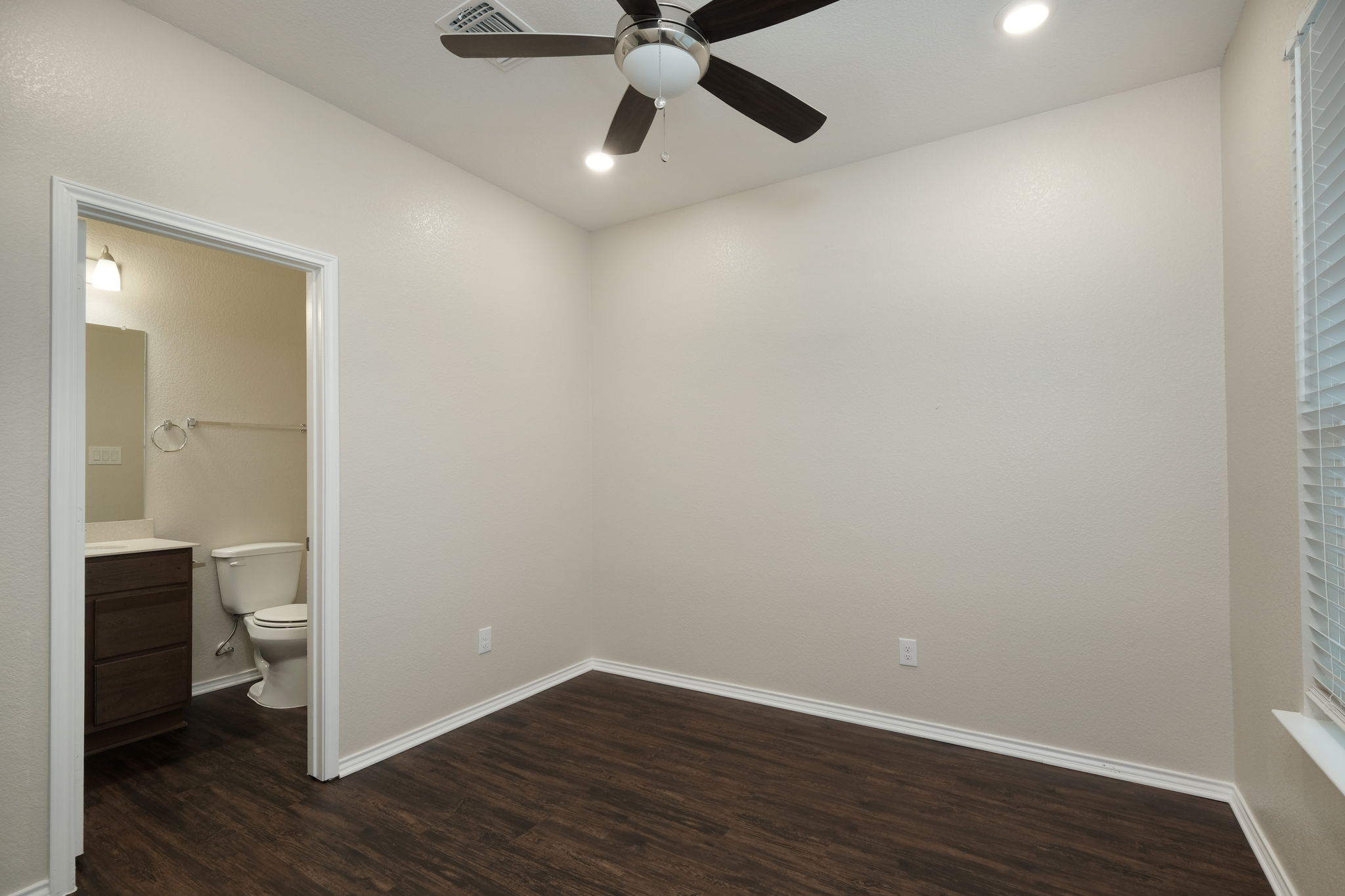 Rich wood-look flooring and an attached bathroom create a private, functional retreat.
