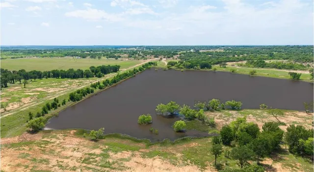 an aerial view of a houses with a yard and lake view in back