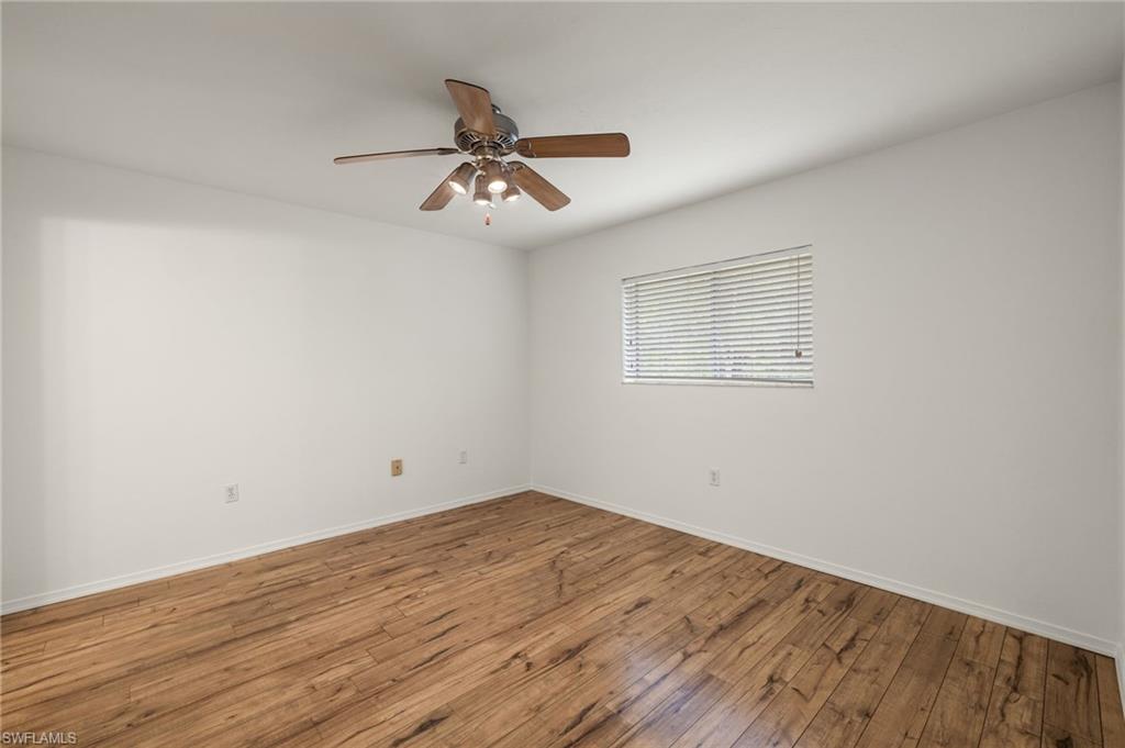 136 Cypress Way East, Unit 507 Naples, FL 34110 - Photo 11 of 21 an empty room with wooden floor fan and windows