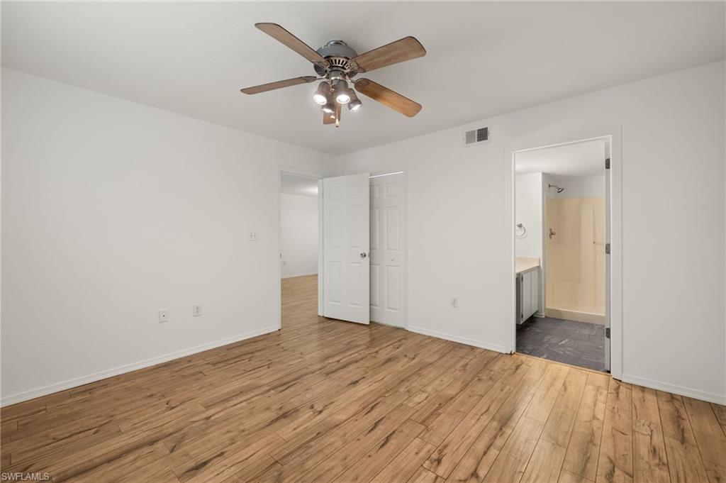 136 Cypress Way East, Unit 507 Naples, FL 34110 - Photo 13 of 21 an empty room with wooden floor and ceiling fan
