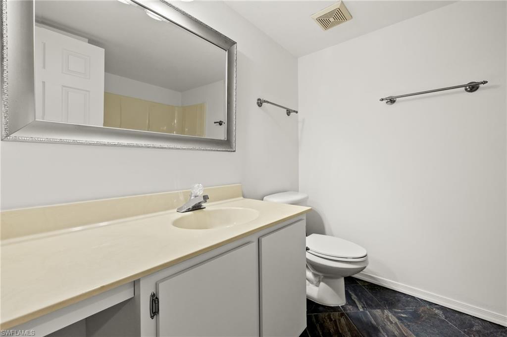 136 Cypress Way East, Unit 507 Naples, FL 34110 - Photo 18 of 21 a bathroom with a sink a toilet and a mirror