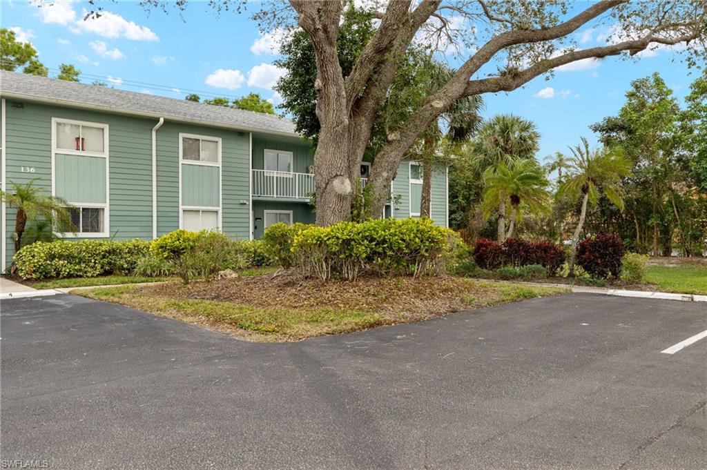 136 Cypress Way East, Unit 507 Naples, FL 34110 - Photo 21 of 21 a view of a house with a yard and large tree
