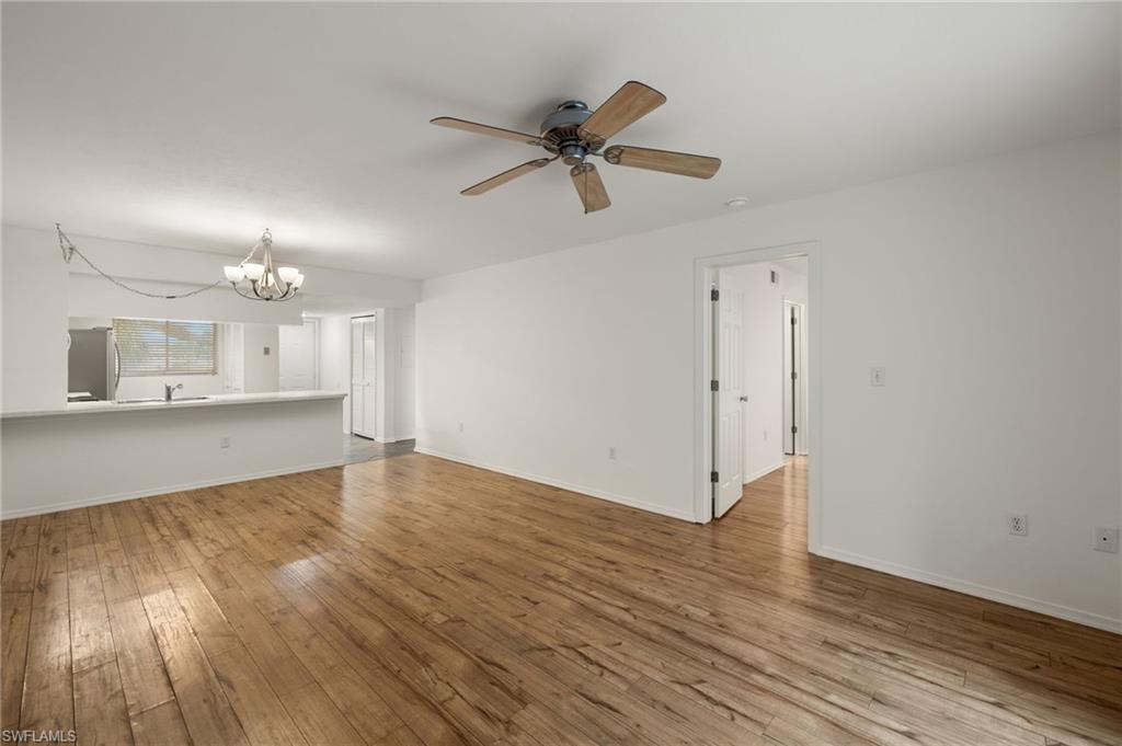 136 Cypress Way East, Unit 507 Naples, FL 34110 - Photo 6 of 21 a view of a kitchen with wooden floor and a ceiling fan