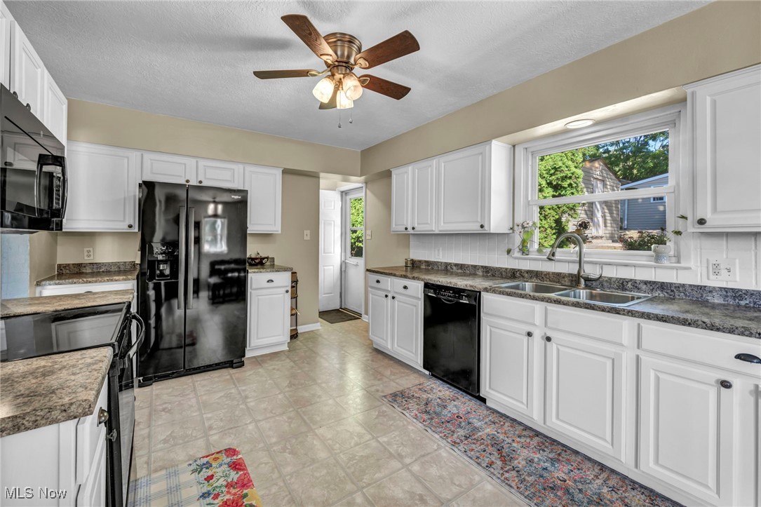 1641 Slusser Road Akron, OH 44305 - Photo 5 of 34 Kitchen with white cabinets, black appliances, dark countertops, plenty of natural light, and a textured ceiling