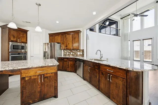 a kitchen with stainless steel appliances granite countertop a sink and dishwasher a refrigerator with wooden cabinets