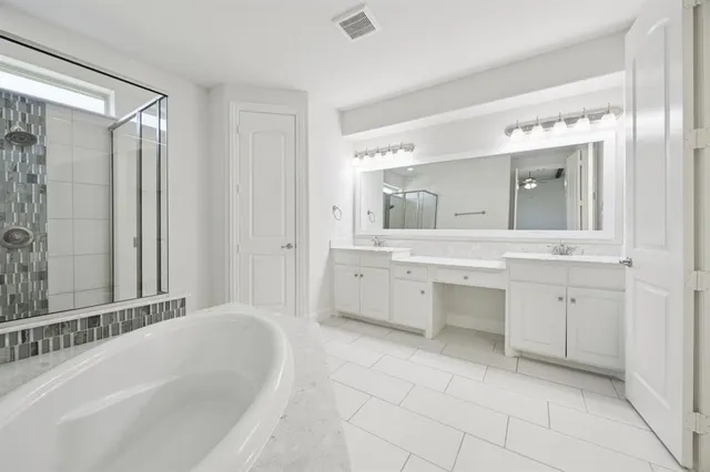 a spacious bathroom with a double vanity sink mirror and bathtub