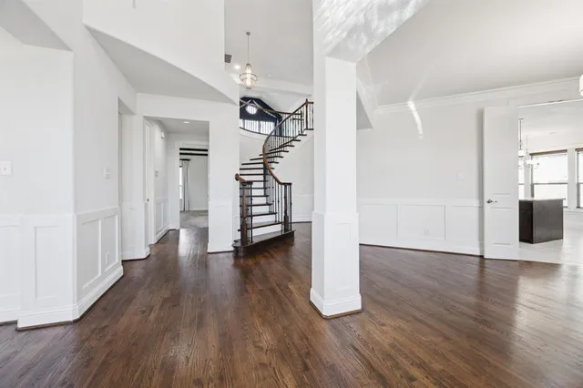 an empty room with wooden floor and staircase
