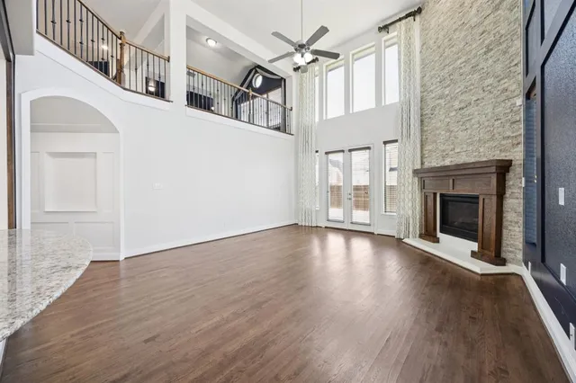 a view of an empty room with wooden floor fireplace and a window