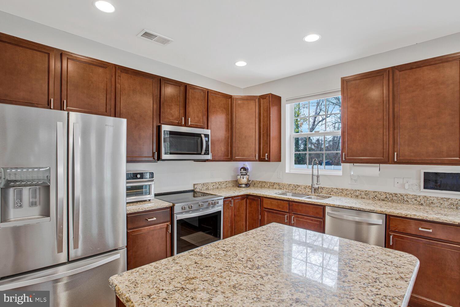 703 Trapper Way Deale, MD 20751 - Photo 5 of 18 a kitchen with stainless steel appliances granite countertop a sink a stove a refrigerator cabinets and a window