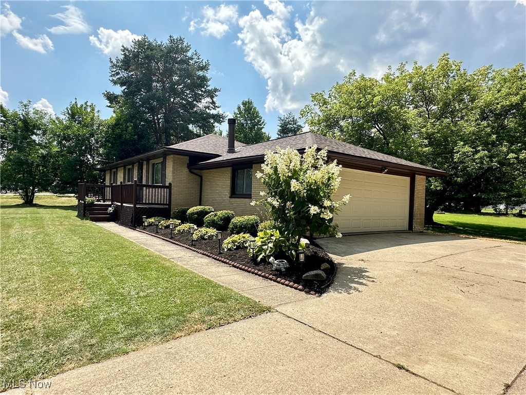 596 Hadcock Road Brunswick, OH 44212 - Photo 2 of 17 View of home's exterior featuring brick siding, a yard, an attached 2-car garage, concrete driveway, and a wooden deck