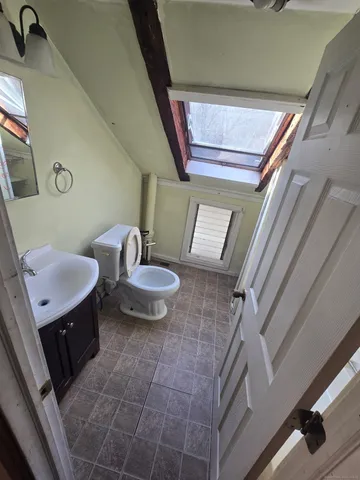 a bathroom with a sink a mirror a toilet and a window