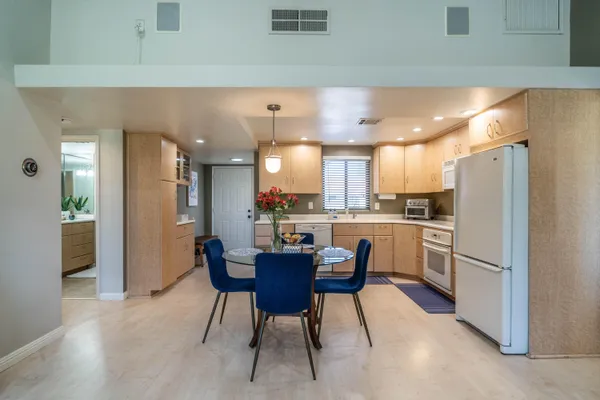 a kitchen with a refrigerator a dining table and chairs