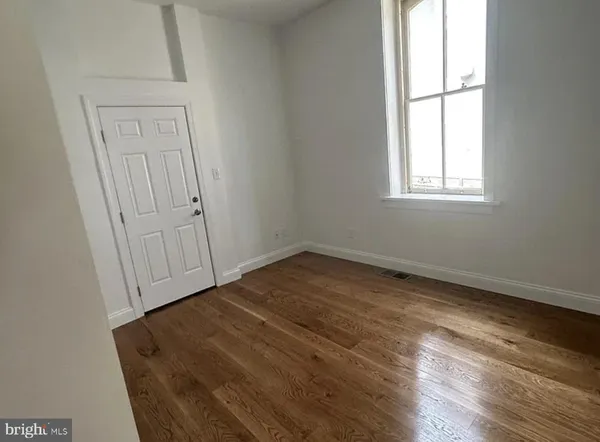 an empty room with wooden floor and window