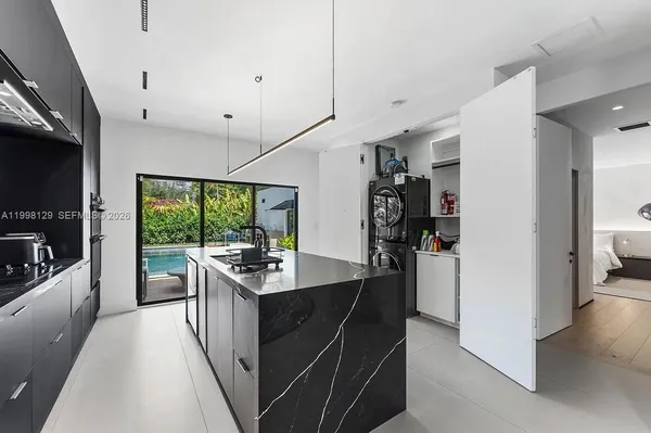 a kitchen with stainless steel appliances granite countertop a refrigerator and a view of living room