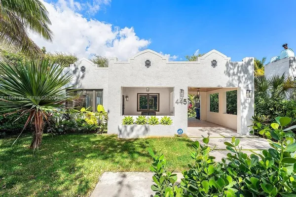 a view of a white house with a yard and potted plants