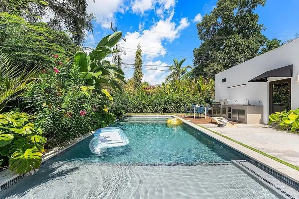 a living room with stainless steel appliances furniture a flat screen tv and a kitchen view