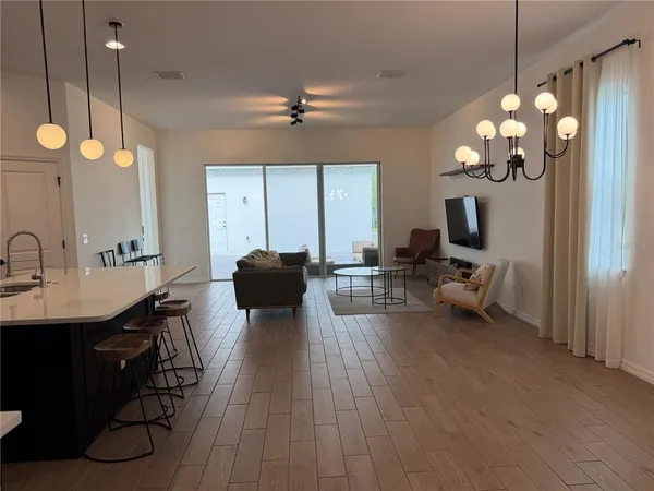 a living room with furniture a chandelier and a flat screen tv
