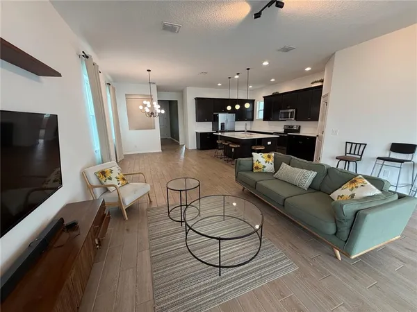 a living room with furniture kitchen view and a flat screen tv