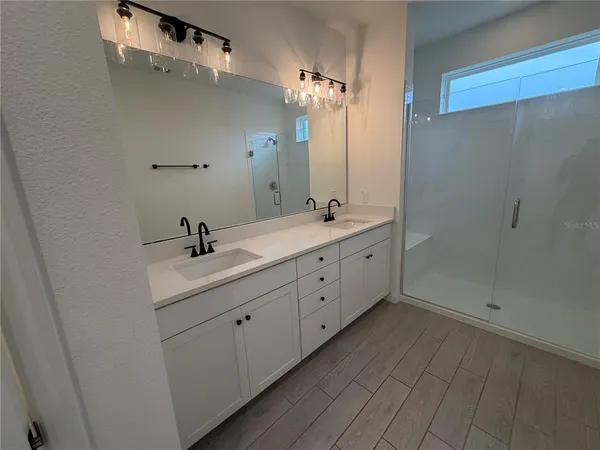 a bathroom with a double vanity sink and mirror with shower