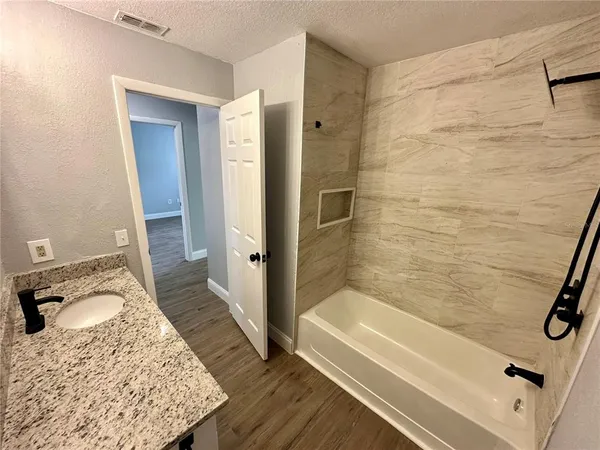 a bathroom with a granite countertop tub sink and mirror