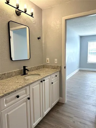 a bathroom with a granite countertop sink vanity and mirror