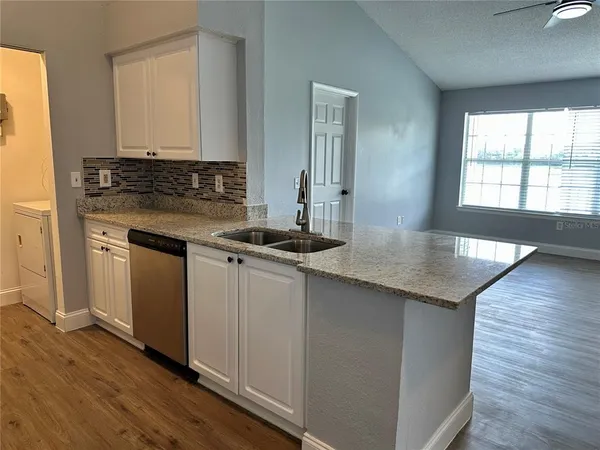 a kitchen with granite countertop a sink cabinets and wooden floor