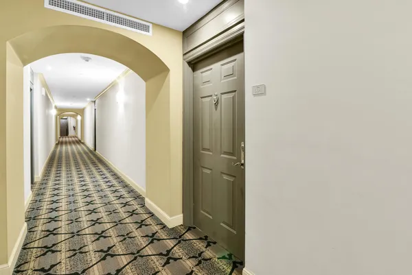 a view of a hallway with wooden floor and a bathroom