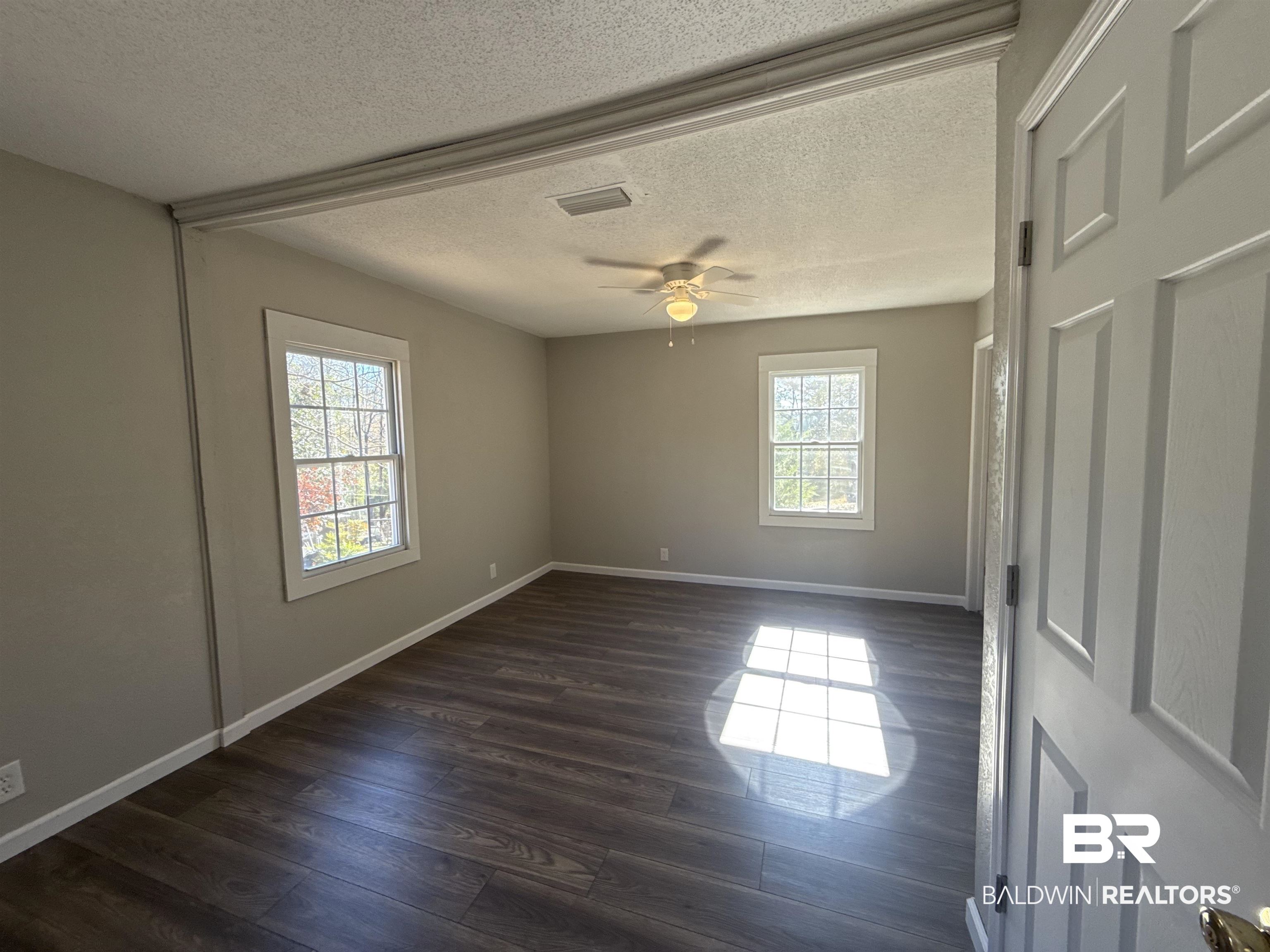 32 Slate Street Atmore, AL 36502 - Photo 12 of 16 Unfurnished room featuring healthy amount of natural light, dark wood-type flooring, a textured ceiling, and ceiling fan
