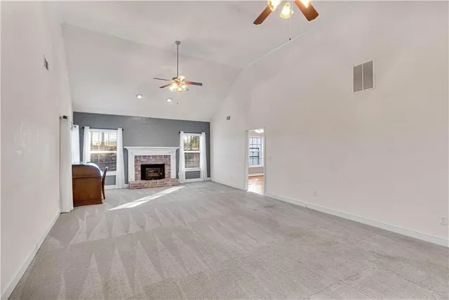 an empty room with windows fireplace and a chandelier fan